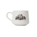 A white ceramic coffee mug featuring a retro-style illustration of a red vintage camper van parked in front of a mountain range with pine trees and a red sun.