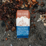 Kaladi Brothers & Salmon Sisters coffee package on a sandy surface with seaweed