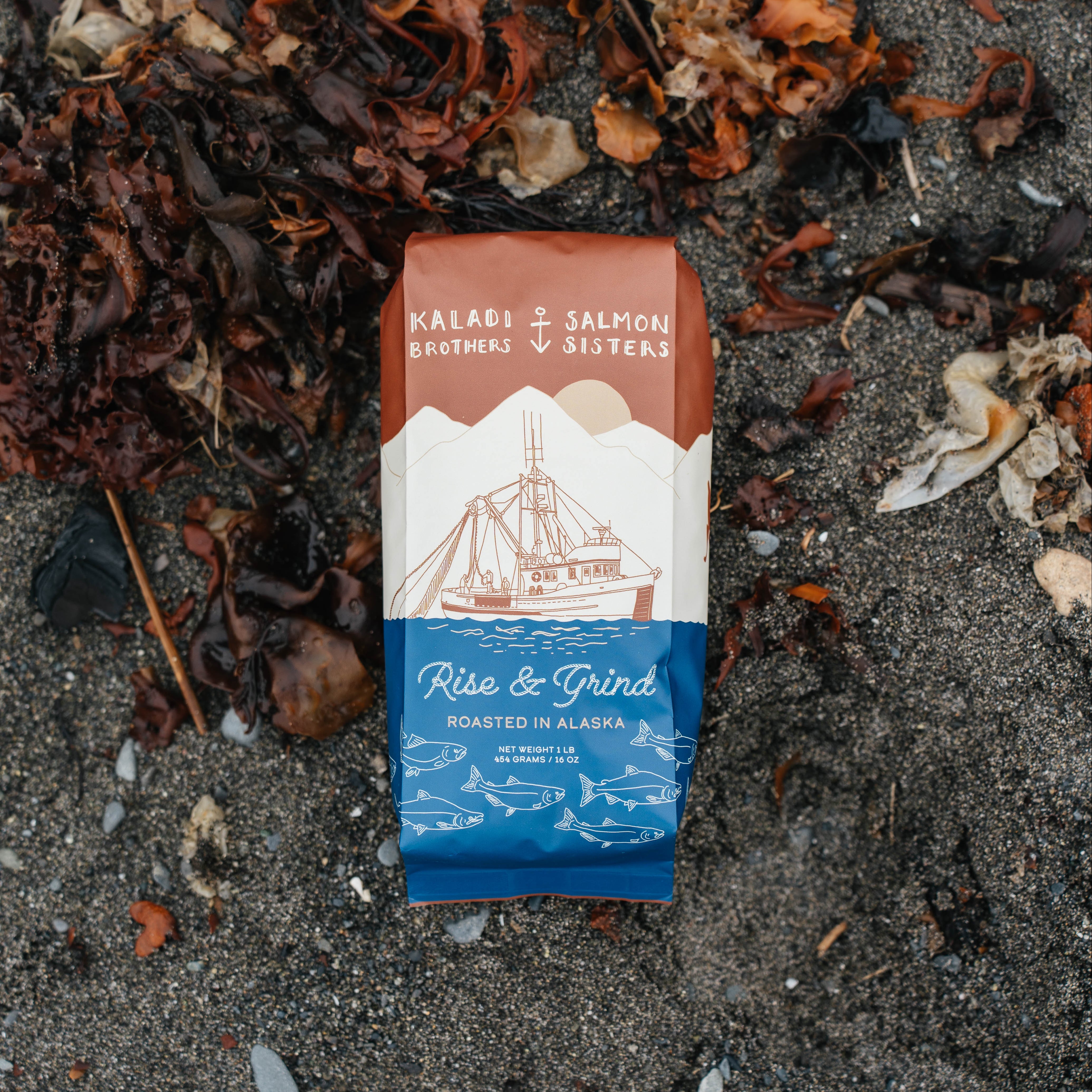 Kaladi Brothers & Salmon Sisters coffee package on a sandy surface with seaweed