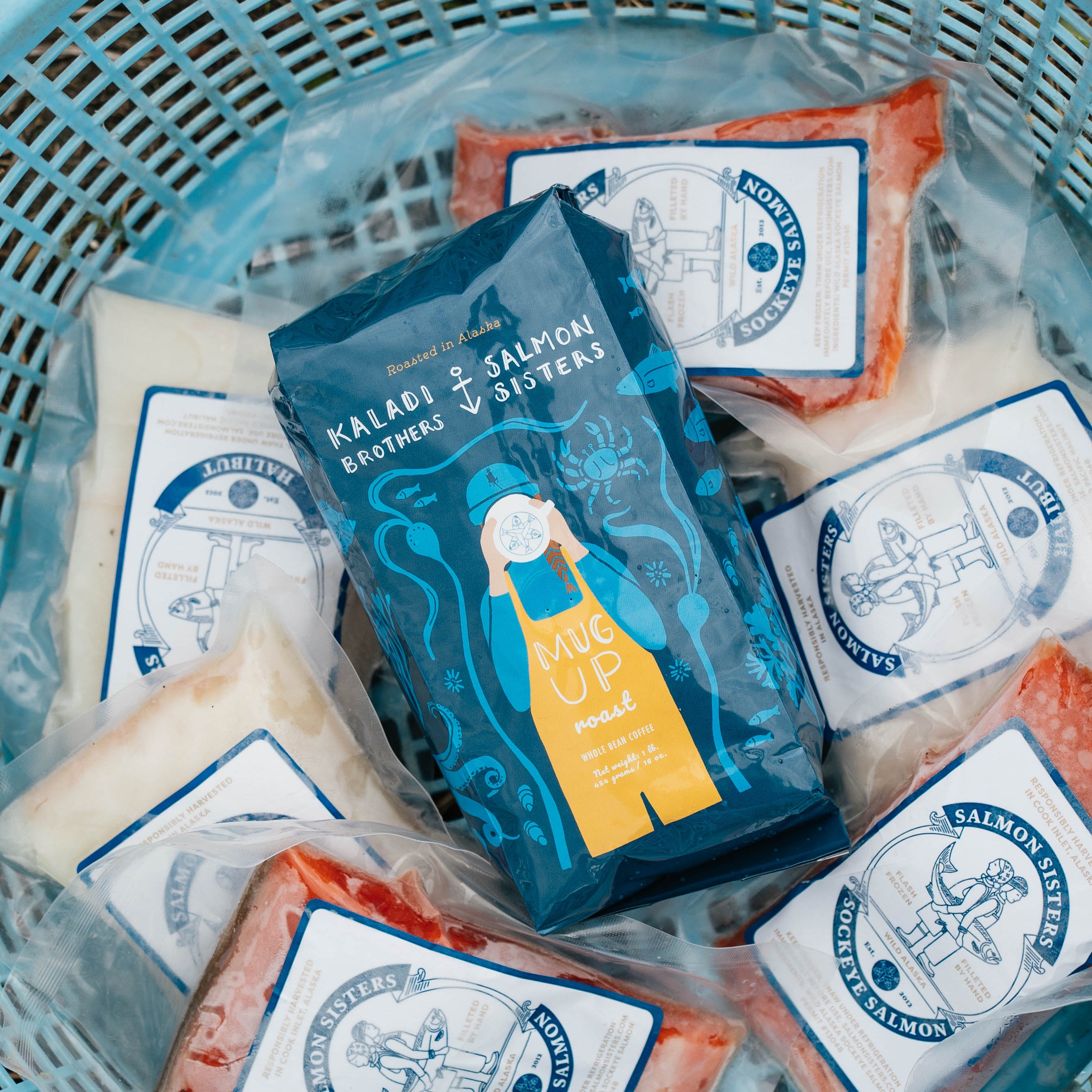 Packages of Kaladi Brothers Coffee & Salmon Sisters seafood in a blue basket
