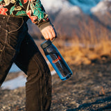Person carrying the navy 33oz Everywhere Bottle outdoors