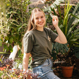 Woman wearing the olive Coffee Cherry T-Shirt in a greenhouse