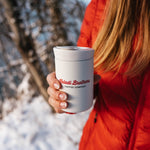 Person in a red jacket holding the white 8oz Nomad tumbler in winter