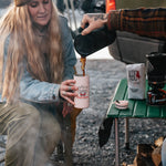 Woman pouring coffee from the MiiR French press at a campsite