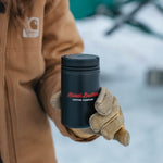 Person in a tan jacket holding the black 8oz Nomad tumbler in winter