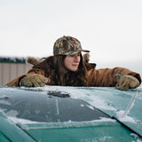 Woman in the Red Goat camo hat leaning on a frosted truck windshield