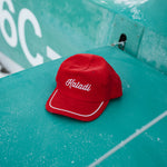 Red corduroy Kaladi hat resting on a teal surface