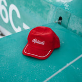 Red corduroy Kaladi hat resting on a teal surface