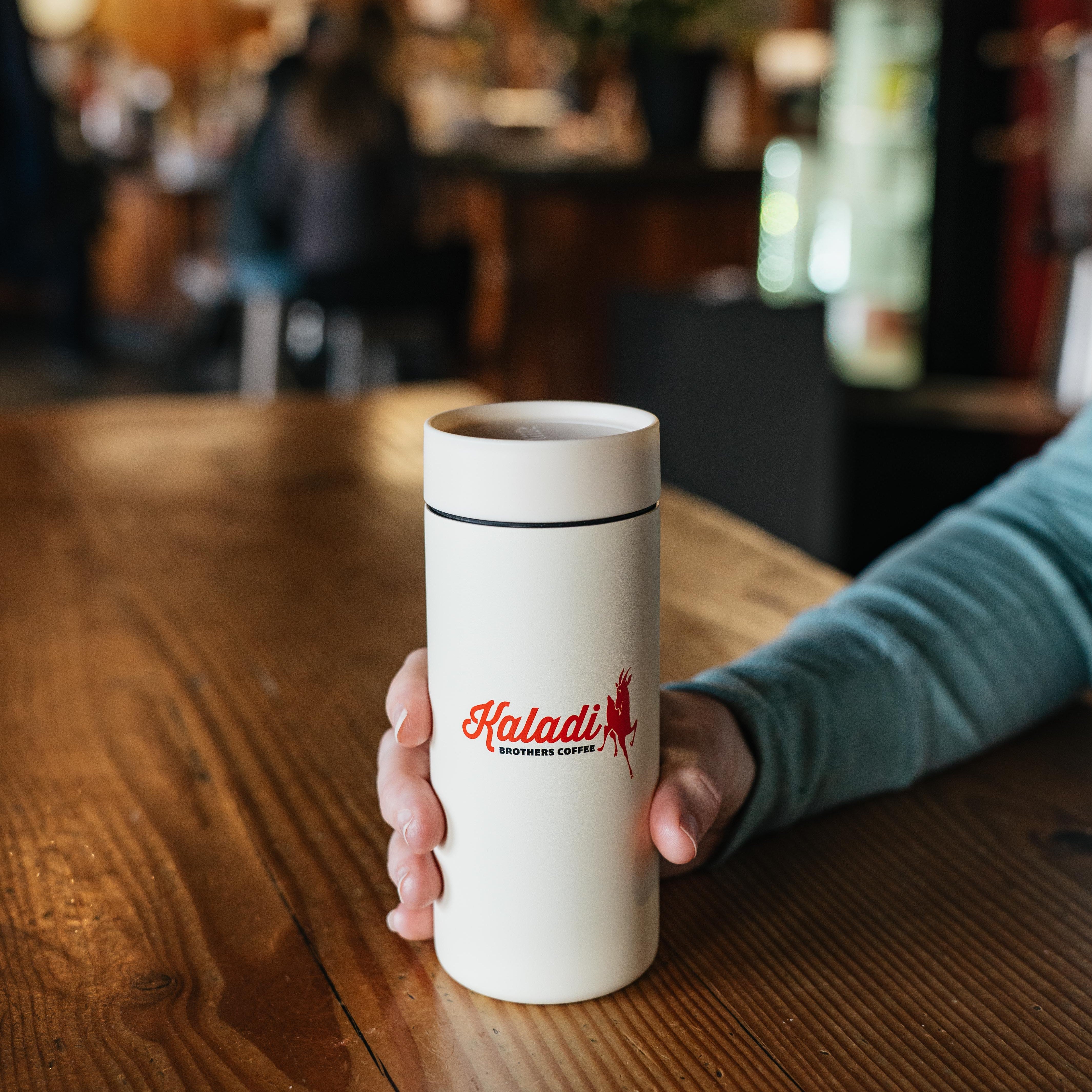 Cream 12oz 360 Traveler tumbler on a cafe table