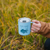 Person holding a blue mug with a design in a grassy field