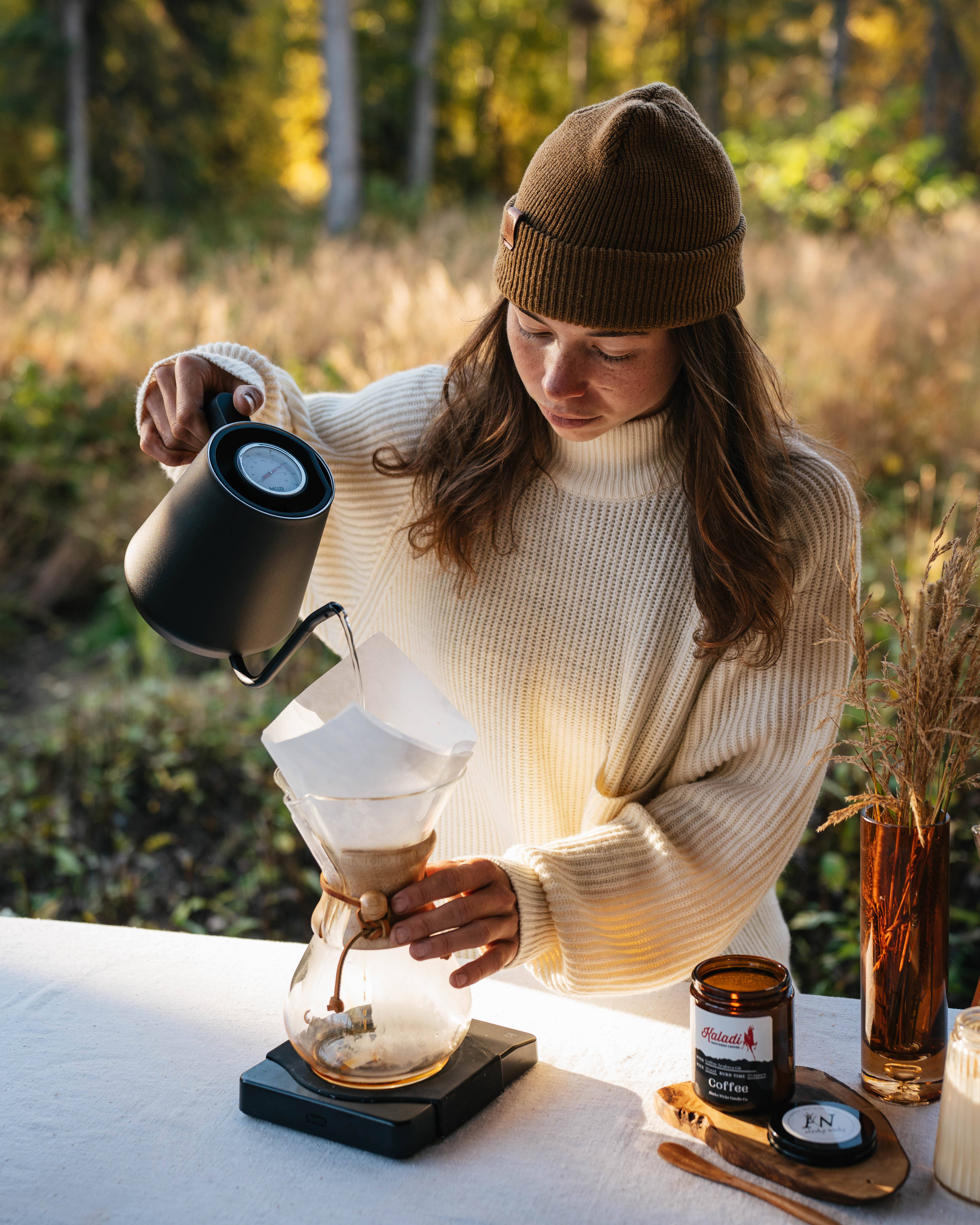 Person making coffee outdoors with a scenic background