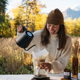 Woman pouring from the black MiiR kettle over a pour-over outdoors