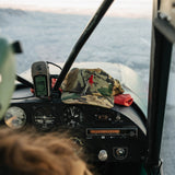 Red Goat camo hat resting on a small plane cockpit dash