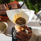 Hands brewing with a Chemex filter outdoors