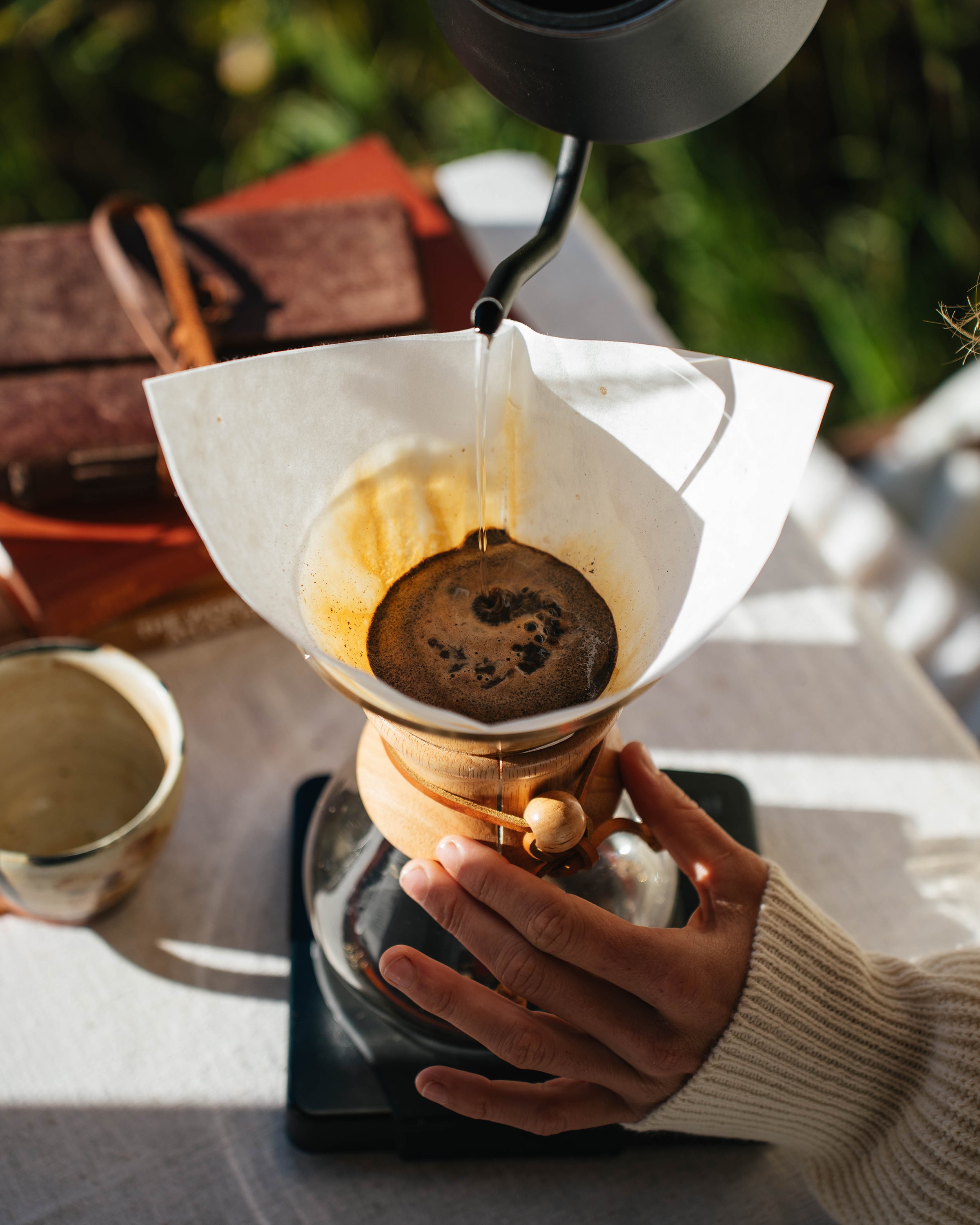 Hands brewing with a Chemex filter outdoors