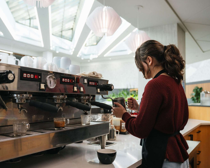 Person making coffee at a coffee machine in a modern kitchen.